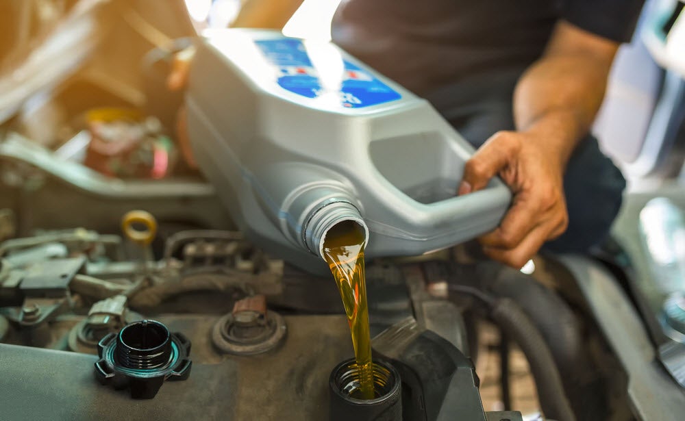 Technician placing new motor oil in a vehicle